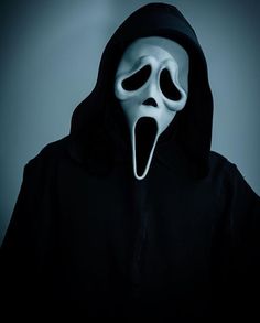 a person wearing a white mask and black hoodie with the mouth open in front of them