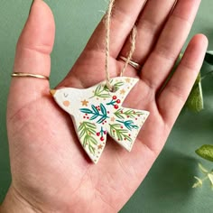 a hand holding a ceramic ornament in it's palm