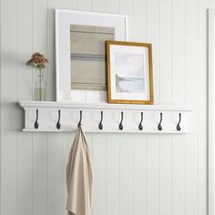 a coat rack with hooks on it next to a white wall and a framed photograph