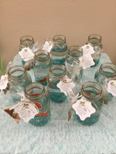 there are many mason jars on the table with tags in them and some goldfish