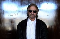 a man wearing sunglasses standing in front of a metal wall