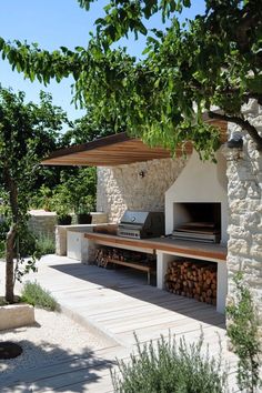 an outdoor bbq with wood stacked on the side and grilling area in front