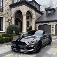 a black and silver mustang parked in front of a house