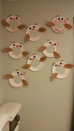 paper plates are arranged in the shape of owls and birds on a gray wall with a white ironing board