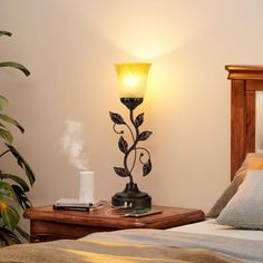 a lamp that is on top of a bed next to a night stand with a phone