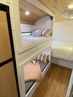 bunk beds are built into the side of a small room with wood flooring and white walls