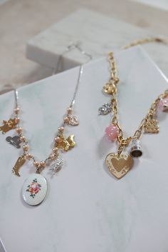 This charm necklace is so sweet and perfect, we can't even handle it. Features mostly vintage mixed-metal charms, hanging on pearls and sterling silver curb chain - to give it just a touch of edginess. 7 charms hang from a strand of sterling freshwater pearls, with a pinkish hue: gold plated vintage teddy bear stainless vintage western hat gold plated cowgirl boot enameled, hand-painted rose charm from the 1960s in center silver plated vintage angel charm gold plated vintage butterfly charm enam Vintage Gold Sterling Silver Necklaces, Vintage Charm Pendant Necklaces, Vintage Charm Necklace With Dangling Pendants, Vintage Pearl Charm Necklaces For Gifts, Vintage Pendant Charm Necklace With Dangling Charms, Vintage Pearl Charm Necklace As A Gift, Vintage Metal Charm Necklace, Dainty Metal Necklaces With Vintage Charm, Dainty Charm Necklace With Dangling Charms