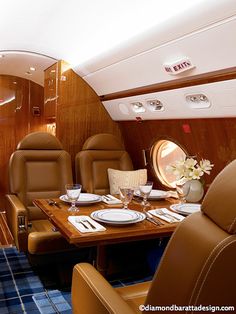 the inside of an airplane with leather seats and tables set up for two people to eat