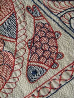 a close up view of some red and blue fish on a white cloth with black stitching