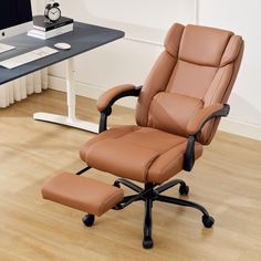 an office chair and footstool in front of a desk with a clock on it