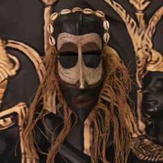 an african mask with long hair and eyeshades is displayed in front of a black background