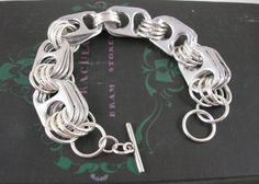 a close up of a silver bracelet on a black box with a cross in the middle