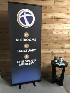 a sign that says restrooms sanctuary children's ministery next to a table with a potted plant on it