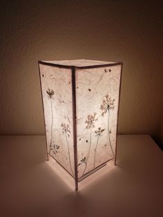 a lamp that is on top of a white table with flowers painted on the side