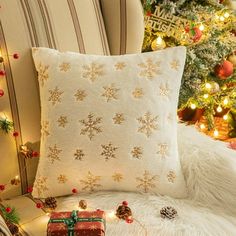 a christmas tree with lights and presents on it next to a couch covered in white fur