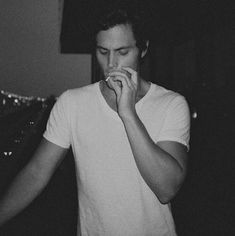 black and white photograph of a young man eating something with his hands while looking at the camera