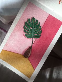 a card with a green leaf on it sitting on top of a bed next to a pillow