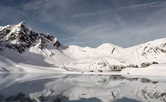 the mountains are covered in snow and there is still water on the lake below them