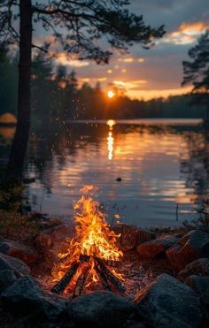 a campfire in the middle of a lake at sunset with trees and rocks around it