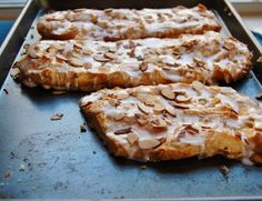 two pieces of food sitting on top of a baking pan covered in frosting and almonds