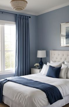 a bedroom with blue walls and white bedding in front of a window that has a chandelier hanging from the ceiling