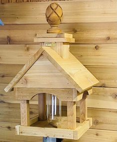 a wooden bird house on top of a table next to a wall with wood paneling