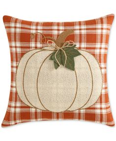 an orange and white plaid pillow with a pumpkin on it