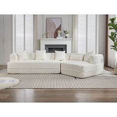 a large white sectional couch sitting on top of a rug in front of a fireplace