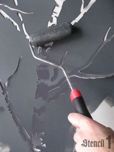 someone is using a brush to paint a tree with black and white leaves on it