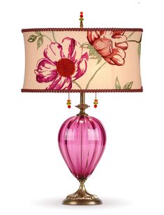 a lamp with a pink glass vase on it and a flower print shade over the base