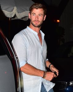 a man standing next to a car holding an umbrella