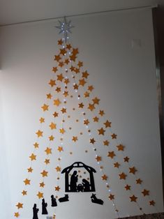 a christmas tree made out of paper with gold stars on it and a nativity scene