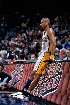 a man standing on top of a basketball court next to a wall filled with fans