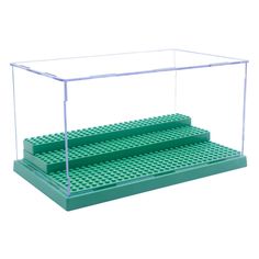 two green lego steps are shown in front of a clear plastic box with the bottom section open