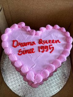 a pink heart shaped cake with the words drama queen since 1965 on it in a cardboard box