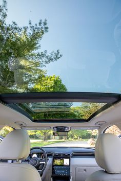 the interior of a car with its sunroof open and trees in the background