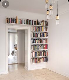 a book shelf filled with lots of books on top of a hard wood floor next to a doorway