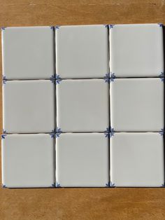 several square white tiles are laid out on a wooden surface