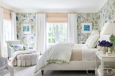 a white bed sitting in a bedroom next to a window with curtains on the windowsill