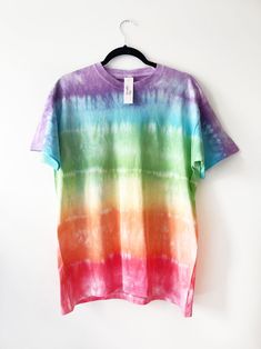 a colorful tie dye shirt hanging on a hanger against a white wall with a black hook