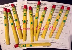 six yellow crayon cake pops are on top of a piece of paper with apples in the background