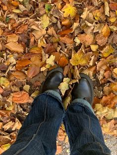 a person standing in front of leaves on the ground with their feet propped up against each other