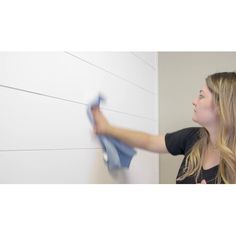 a woman is cleaning the wall with a rag