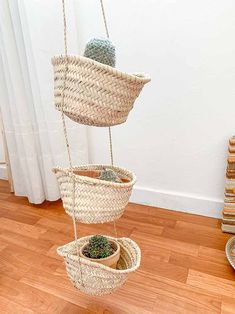 three hanging baskets filled with plants on top of a wooden floor