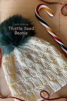 a knitted beanie with a green pom - pom on top and the words, quick knitting thistle seed beanie