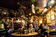 people sitting at tables in a restaurant with lots of decorations hanging from the ceiling above them