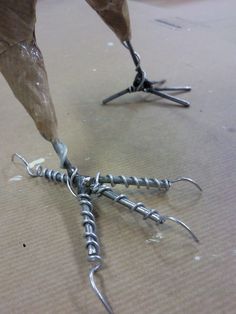 a pair of nails are being used to attach screws on a piece of cardboard