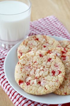 three cookies on a white plate sitting on a red and white checkered table cloth