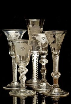 five glass goblets sitting on top of each other in front of a black background