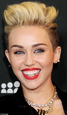 a woman with blonde hair and blue eyes smiles at the camera while wearing a black jacket